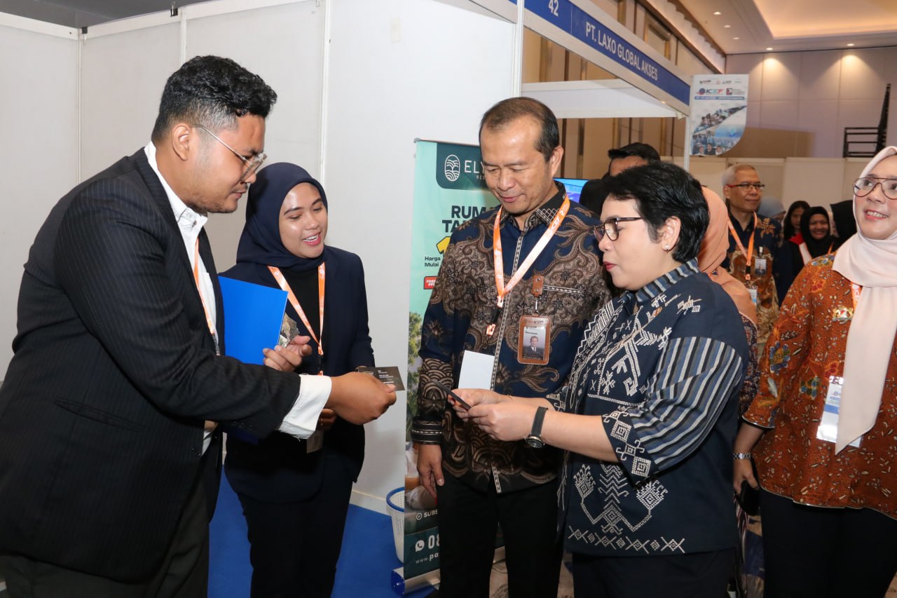 Sejumlah pengunjung berbincang dan memegang kartu di sebuah stan pameran.