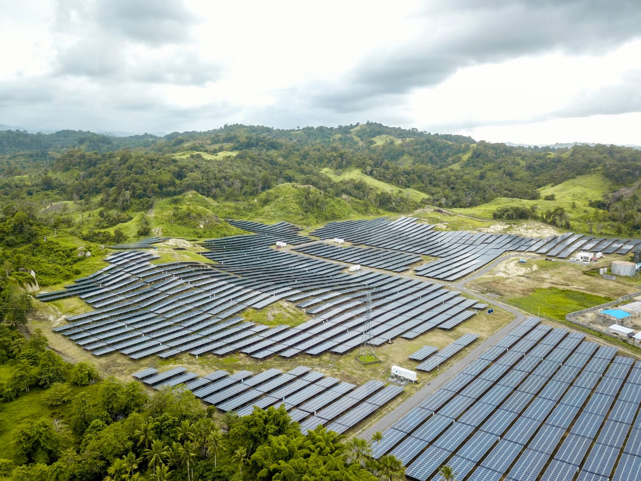 Foto udara hamparan panel surya PLTS Likupang di antara perbukitan hijau di Minahasa Utara.