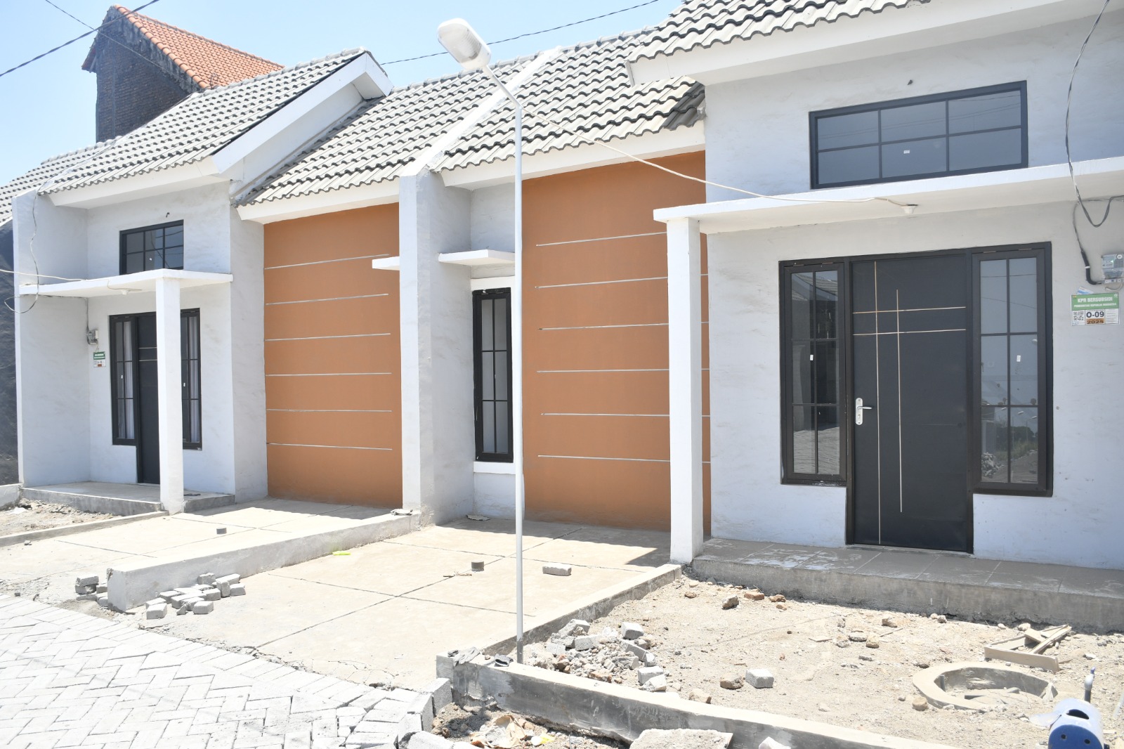 Deretan rumah tapak dengan fasad putih dan jingga pada publikasi BP Tapera tentang rumah subsidi.